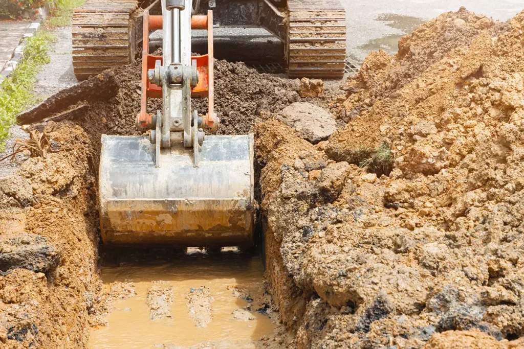 Backhoe dig repair broken water line pipe main plumbing on road