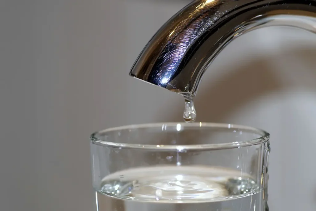 Water dripping from a faucet into a glass